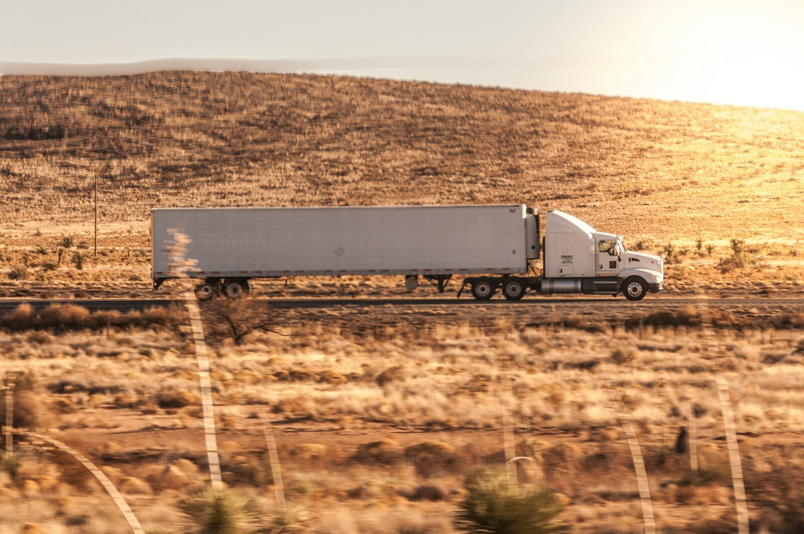 a white semi truck driving down a rural road